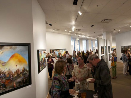 A group of patrons gathers around a few paintings in a white-walled gallery