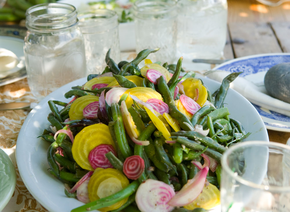 A white plate of fresh green, yellow and pink veggies