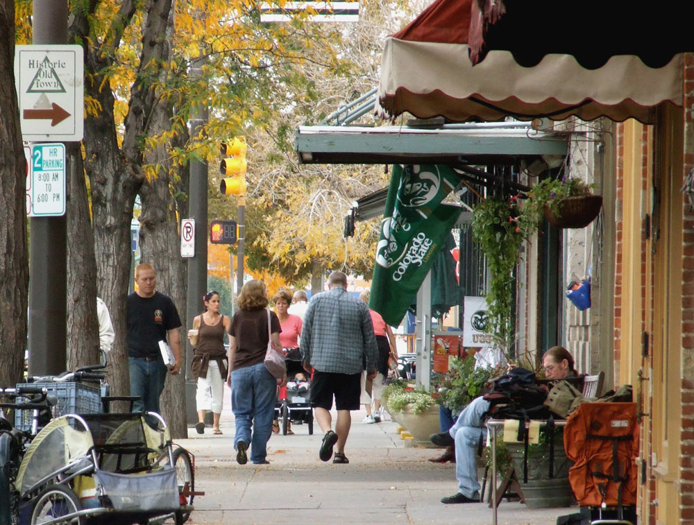 People walk along a downtown street full of stores