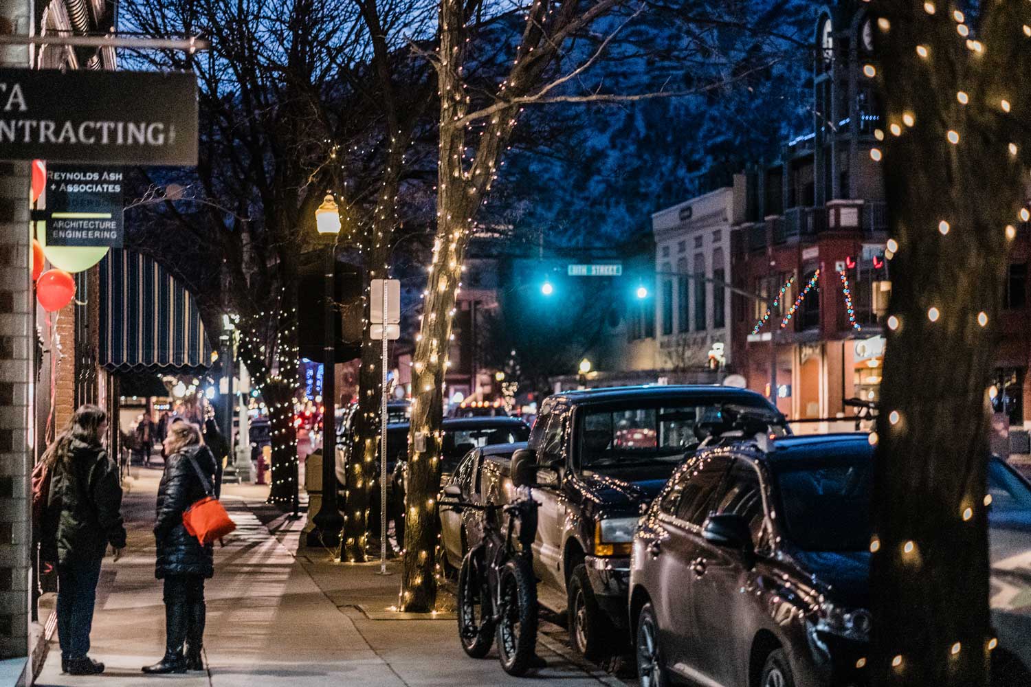 Shoppers walk along a historical Main Street with shops and white lights lining the way