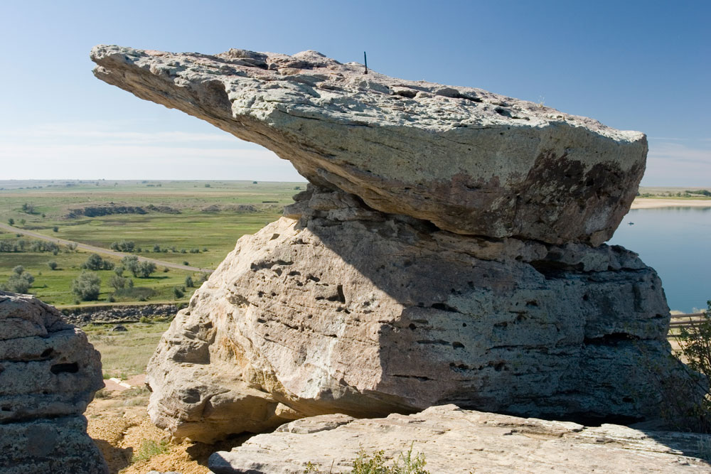 A grey slab of rocks is perched on the shore of the lake