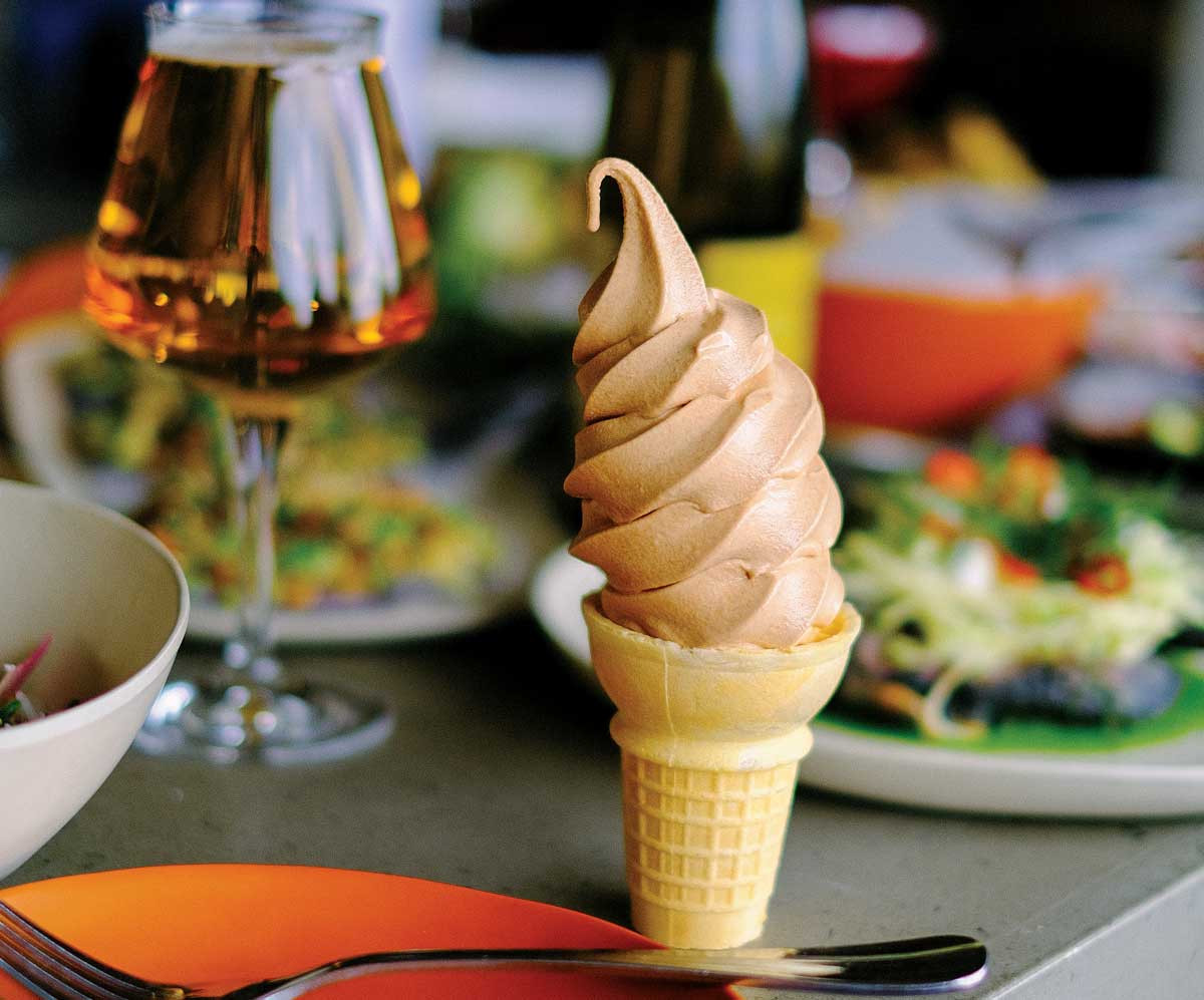 An ice cream cone and glass of wine sit on a table at a restaurant