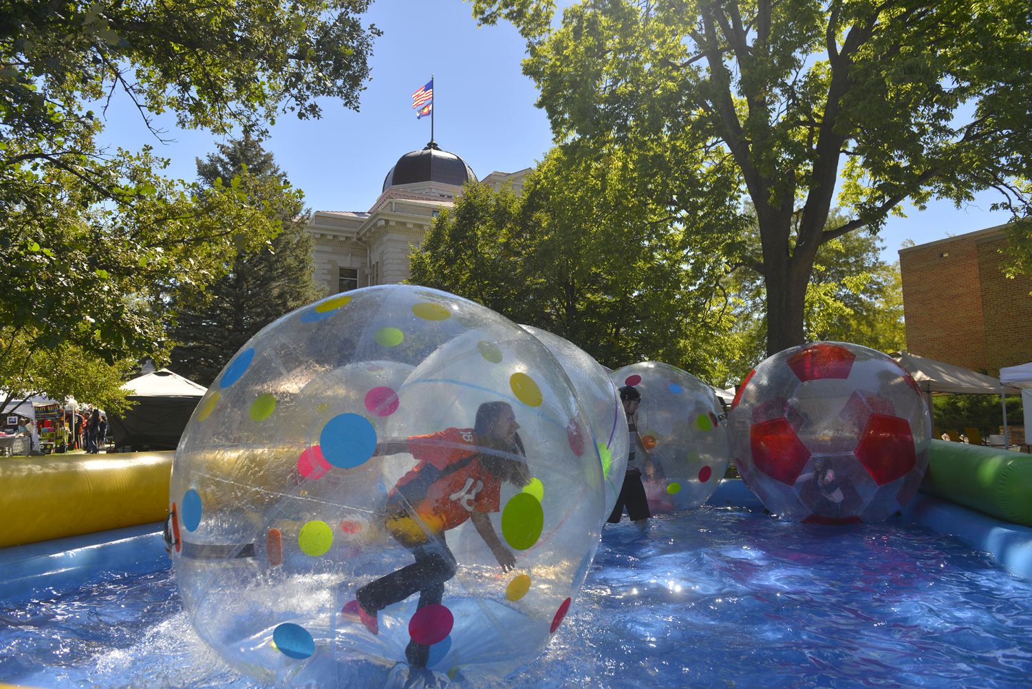 Children play in giant plastic balls atop a pool of water on the square of the county courthouse.