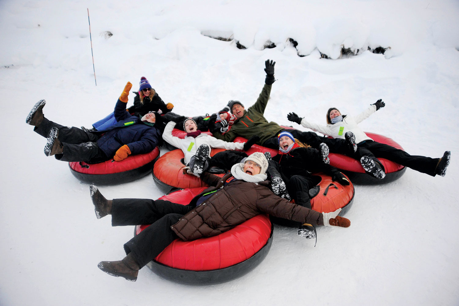 A group of snow-tubers have fun on a snowy track