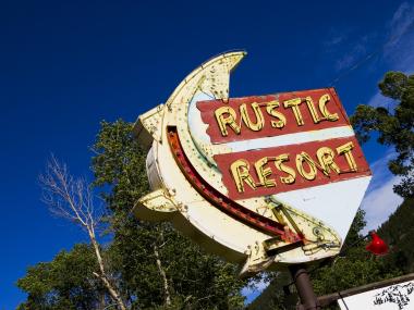 An old roadside sign welcomes visitors to the Rustic Resort in Rustic, Colorado