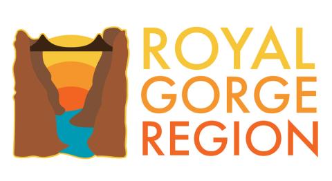 Royal Gorge Region Logo — an illustration of a blue river running through a brown canyon with a bridge stretching over it and a sunrise in the background