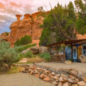 An airstream trailor with a wooden porch sits below redrock formations at Canyon Hideout Bungalow in Cortez