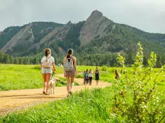 Boulder's Flatirons Boulder Flatirons in summer with two women walking a dog in the foreground.