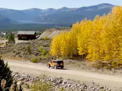 Fall in Leadville Two Jeeps drive a gravel road with golden trees in background in Leadville.