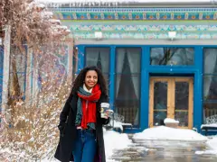 Boulder Dushanbe Teahouse A person holding a to-go cup of tea walks out of Boulder Dushanbe Teahouse's peacock blue and teal tiled doorway on a walkway lined with snow