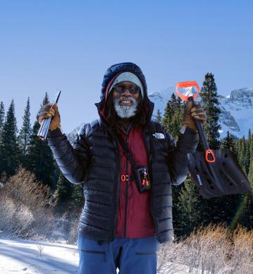 Person stands in snowy backcountry with avalanche rescue equipment