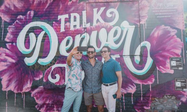 Men pose before a Talk Denver to Me mural in Denver's RiNo neighborhood