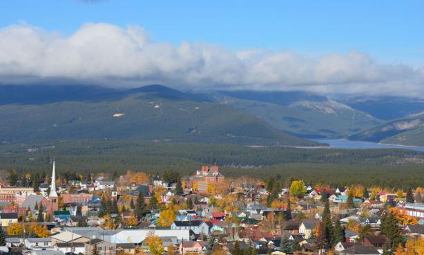 Bird's-eye view of Leadville in autumn with mountains, fluffy white clouds and blue sky overhead.