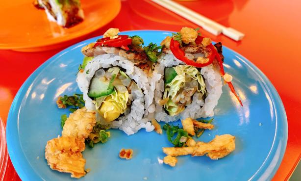 Colorful sushi rolls on a blue plate with chopsticks in the background at Sushi-Rama in Denver's RiNo neighborhood