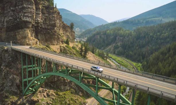 A car drives across a bridge in Colorado with rolling mountains in the background on the way to Red Cliff