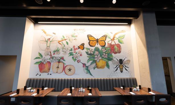Nature-based mural and tables at Apple Blossom restaurant at the Hyatt Centric Downtown Denver