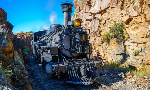 An engine on the Durango & Silverton Narrow Gauge Railroad climbs the rails between two rocky canyon walls