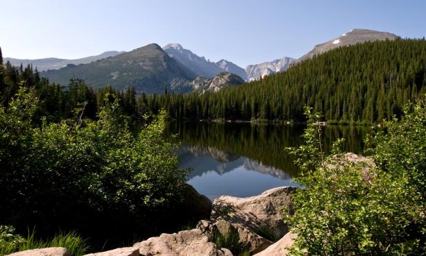 An alpine lake reflects the surrounding peaks on a sunny summer day  in Rocky Mountain National Park