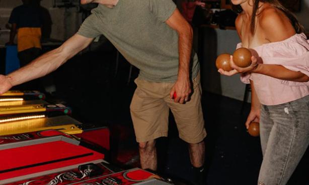 A couple in casual clothing laugh and smile as they play a round of skee-ball in Fort Collins.
