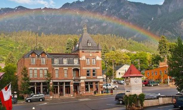 A full rainbow is seen arching over a Victorian-era brick building