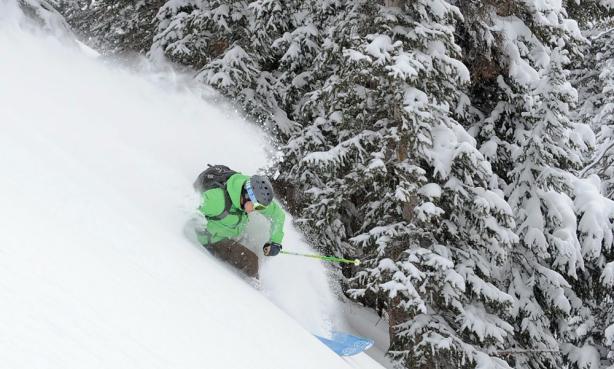 A person in a bright green jacket skis down a mountain in Colorado's backcountry