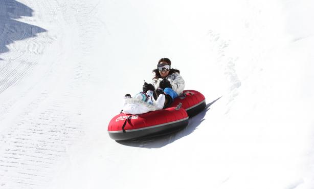 A person zooms down a snow-covered hill on a red tube in Colorado.