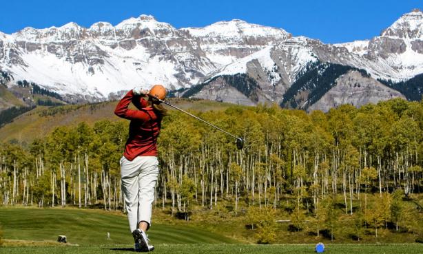 Golfer post swing with mountains in the background