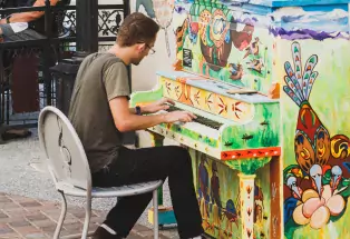 Man playing a colorfully painted piano