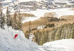 A skier at Crested Butte Mountain Resort with the village in the distance