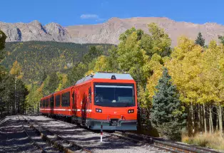 Pikes Peak train in a golden aspen forest with mountains in the background