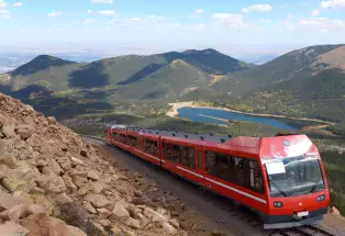 Pikes Peak train with alpine lake and mountains in the background