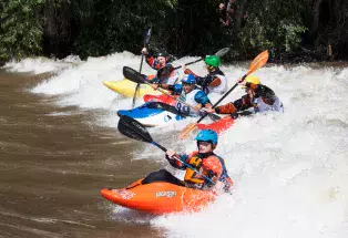 Kayakers paddling through a wave