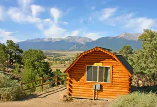 Cabin at KOA in Buena Vista during daytime, surrounded by mountains.