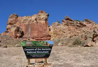 Canyons of the Ancients red-rock formations with sign in foreground