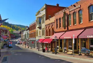Downtown Central City with red-brick buildings with red awnings on a blue-sky day.