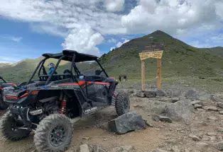 ATVs sit in front of a sign for the Continental Divide in the Colorado mountains