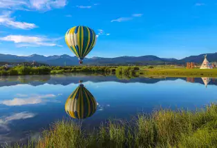 Hot-air balloon reflected in still waters with mountains in the background near Winter Park