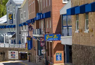 Exterior of Grand Z Casino Hotel on a sunny day. Many windows with blue awnings.