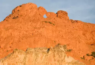 Garden of the Gods red-rock formation against blue sky; see the keyhole within the rocks near the top of the orange and yellow rock mass..