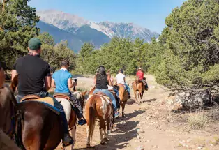 Horseback riders on a trail with mountain peaks in the foreground