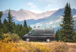 Black campervan with Native Campervans logo on the side parked in front of a mountain range. 