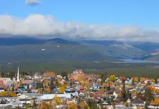 Bird's-eye view of Leadville in autumn with mountains, fluffy white clouds and blue sky overhead.