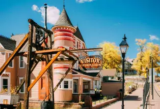 A pink and red Victorian home stands behind Leadville's visitor-information sign.