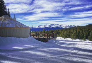 Tennessee Pass Cookhouse surrounded by snow with mountains in the distance in Leadville