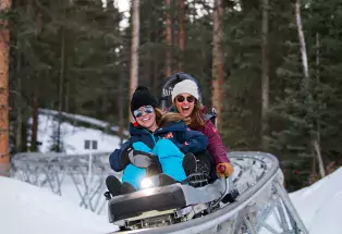 Two women ride alpine coaster in the winter