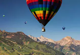 Multicolored balloons above a picturesque mountain background.