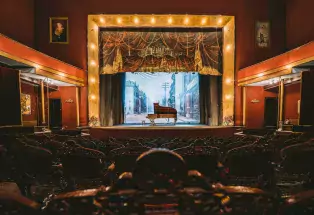 Piano on a stage inside of an opera house.
