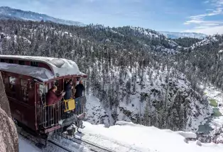 Durango Train caboose rounding a bend with a snowy canyon and flocked trees in the background