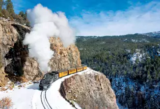 Durango & Silverton Narrow Gauge Railroad train winding around a snow-covered cliff