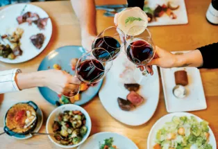 Wine glasses clink over a table filled with delicacies at Urban Farmer in Denver